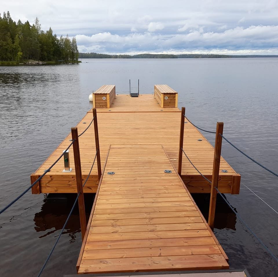 Valmis puulaituri oleskelutasoineen tyynessä järvimaisemassa